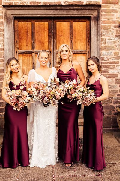 Bride in Emmy Mae bridal gown and bridesmaids in burgundy satin bridesmaid dresses.