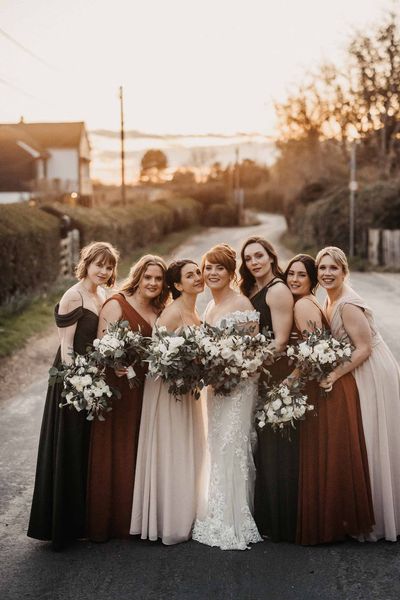 Bride in lace Maggie Sottero wedding dress with bridesmaids in earth toned dresses for wedding at Cooling Castle Barn.