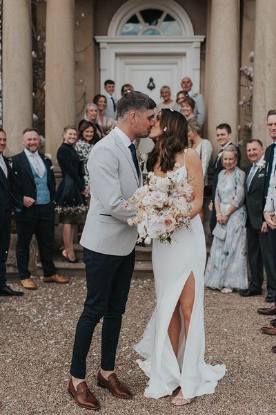 Bride in Alexandra Grecco wedding dress with split leg with groom. 