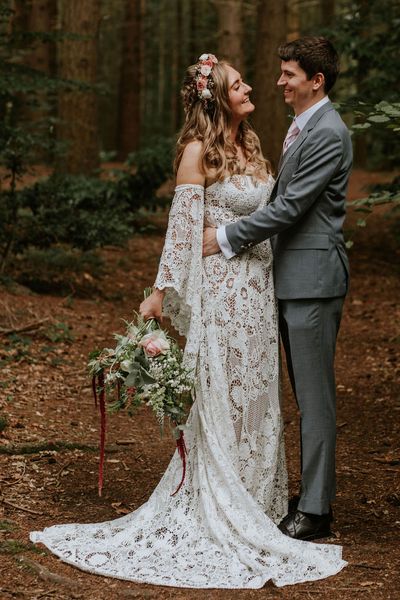 Bride in strapless lace medieval wedding dress with custom sleeves with groom in woodland after handfasting ceremony. 