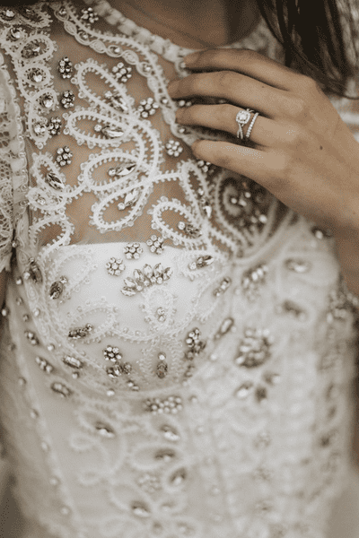 Bride in a bejewelled wedding dress wearing a sparkly engagement and wedding ring.