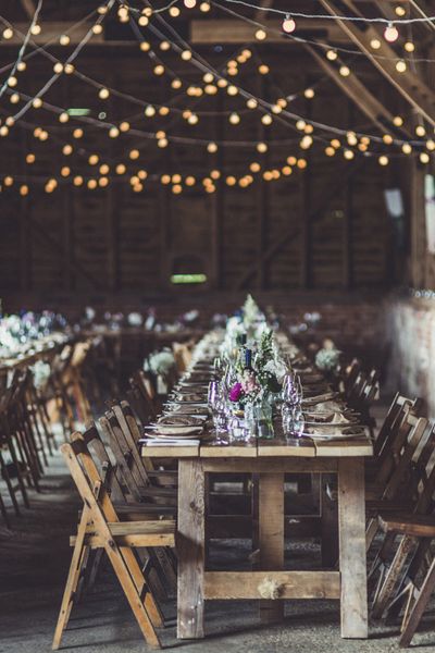 Rustic wedding ideas with fairy lights, trestle tables, tree slices, flowers in jars and wooden signs 