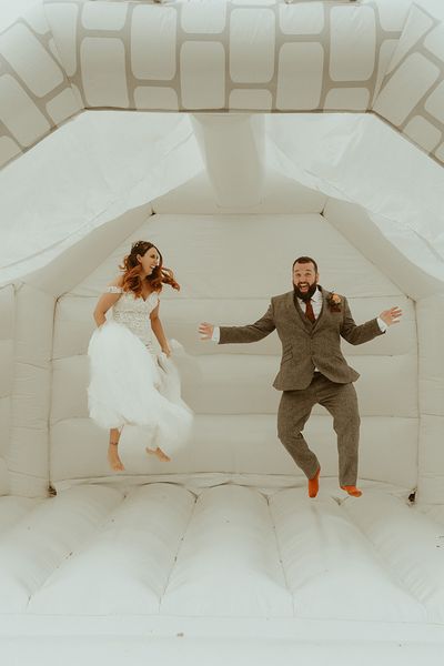 Bouncy castle wedding with bride and groom jumping on the white bouncy castle.