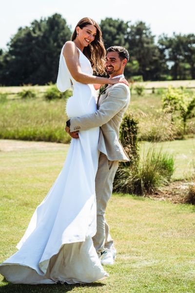 Groom picking up his bride on heir wedding day at Oakwood at Ryther. They are being playful and smiling. 