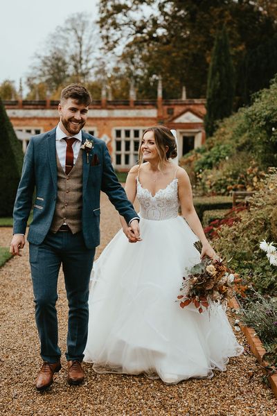 Bride in Blush by Hayley Paige holding autumnal wedding bouquet with groom in blue suit for Oxnead Hall wedding,