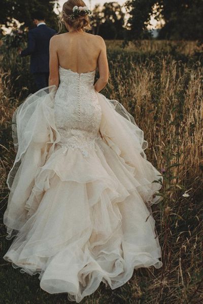 Mermaid wedding dress worn by the bride running through a field.