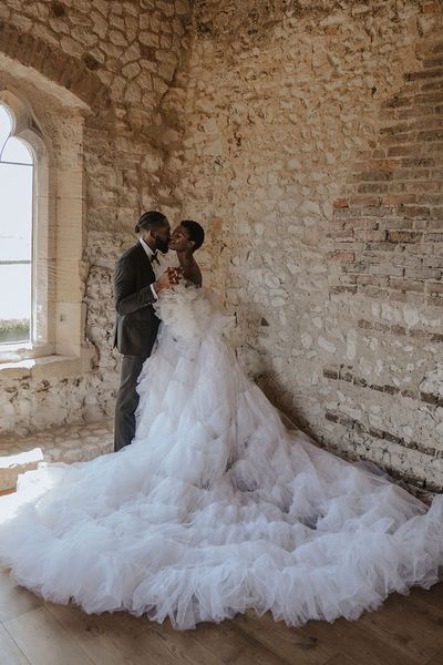 Bride wearing a statement tulle Millia London wedding dress with groom in black tuxedo