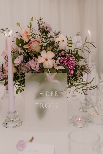 Small arrangement of purple wedding flowers and lilac taper candles.