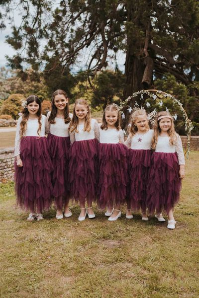 Six flower girls in purple tulle layered flower girl dresses with lace top detail