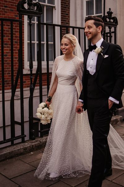 Bride in a shimmery Jesus Peiro wedding cape with groom in black tie. 