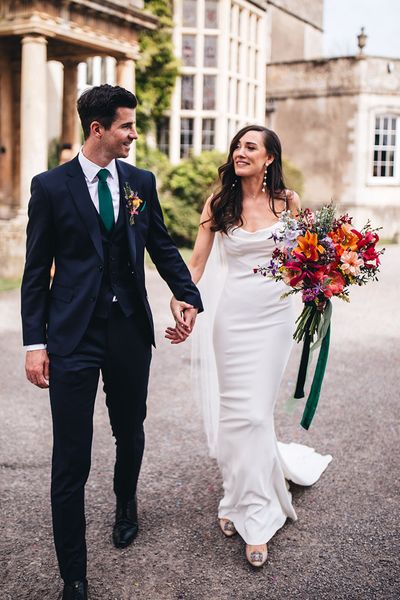 Kyha wedding dress worn by bride walking with groom at Elmore Court.