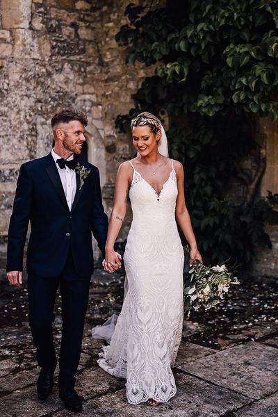 Bride in lace wedding dress and groom in black tie walk together at Athelhampton House.