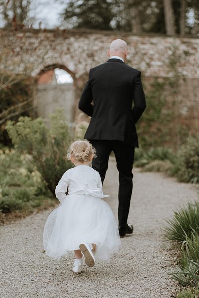 Flower girl in a white dress and cardigan to play a role in a wedding