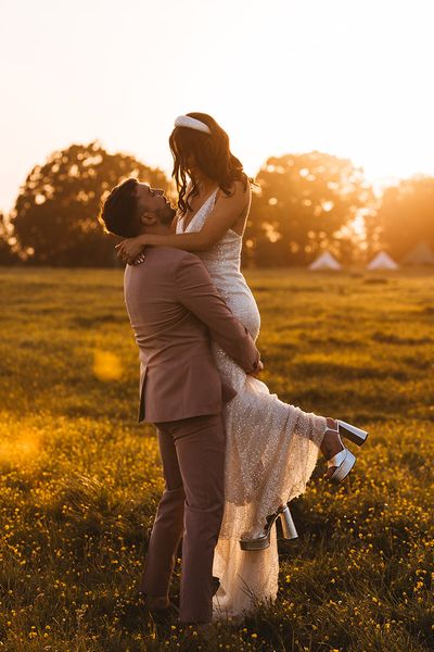 bride is lifted up by the groom for their golden hour wedding photos