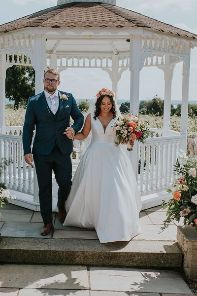 Bride in white dress and pink flower crown with groom at outdoor wedding at St Tewdrics House