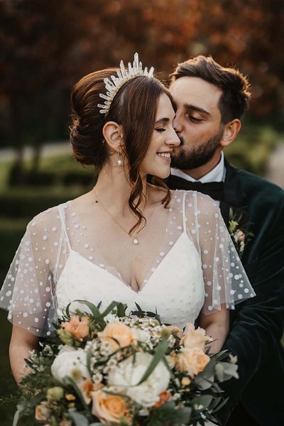 Bride in a dotted wedding dress and quartz crystal crown with the groom in a velvet suit jacket.