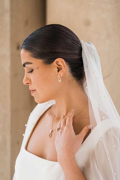 Bride in square neck wedding dress with sheer pearl embellished bridal veil and dainty silver pearl bridal jewellery