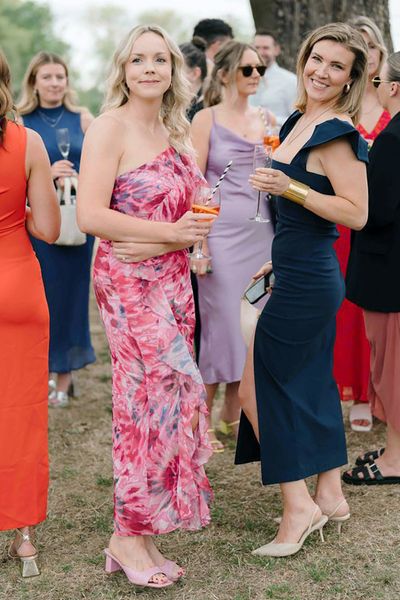 wedding guests wearing a pink patterned and navy wedding guest dress for outdoor wedding