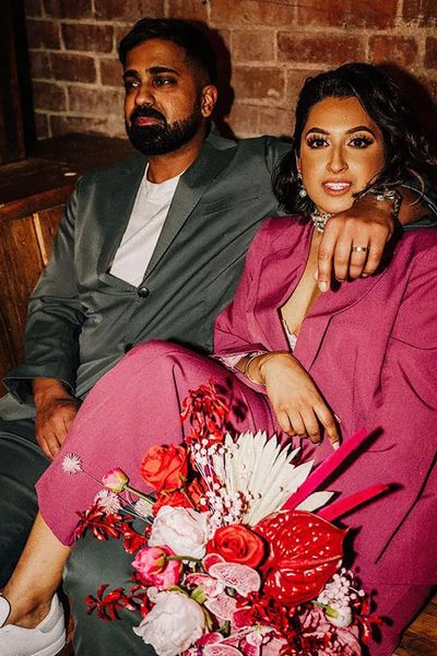 Bride wearing pink colourful wedding suit and the groom wearing a dark green suit for the wedding reception