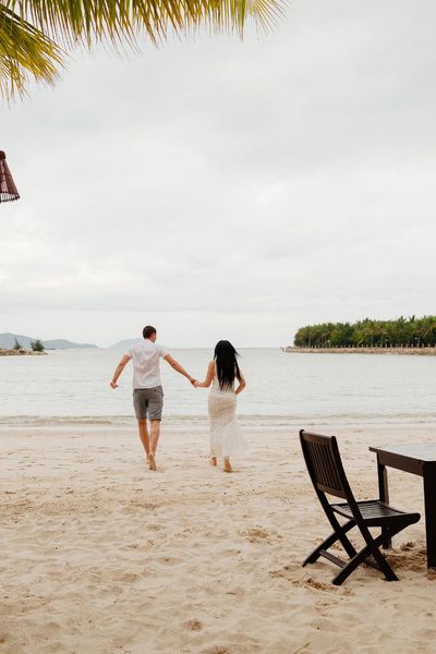 couple joyfully running along the beach towards the sea, celebrating their honeymoon