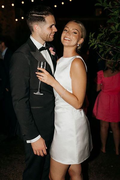 Bride in short wedding reception dress for the city wedding with the groom in a black tux