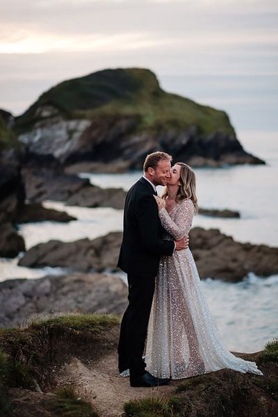 bride wearing a sparkly bespoke wedding dress by the sea on wedding day with groom