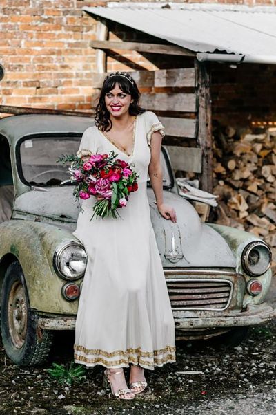 Bride wears vintage wedding dress with gold trim detail 