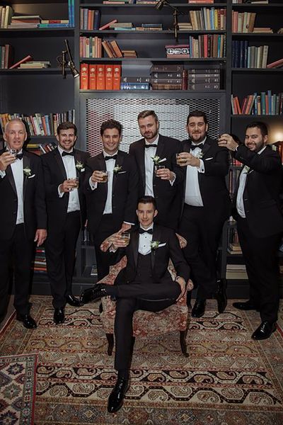 groom and groomsmen taking group photo on wedding day wearing matching black tuxedos