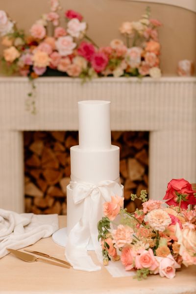 Three tier white wedding cake with satin bow feature. Image by Nataly J Photography 