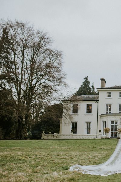 A gorgeous country house sitting on the hill, with bride and groom in full view 