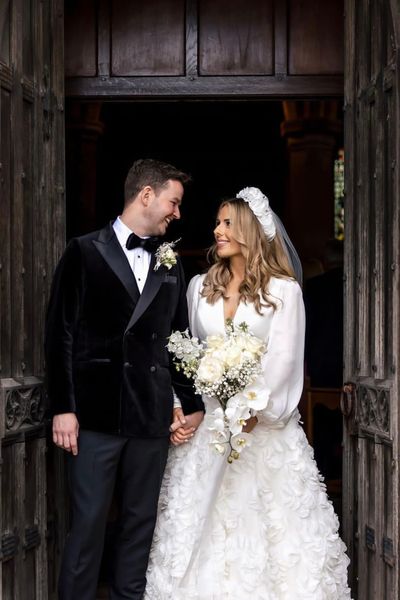 Cheshire wedding featuring an array of white blooms and green foliage.  We created a stunning bouquet of the finest white reflexed roses, Gypsophila, Phalaenopsis Orchids and Delphiniums tied off with a silk drape. The grooms buttonhole consisted of white spray roses and dried blooms and foliage.  Image: SMH Photography