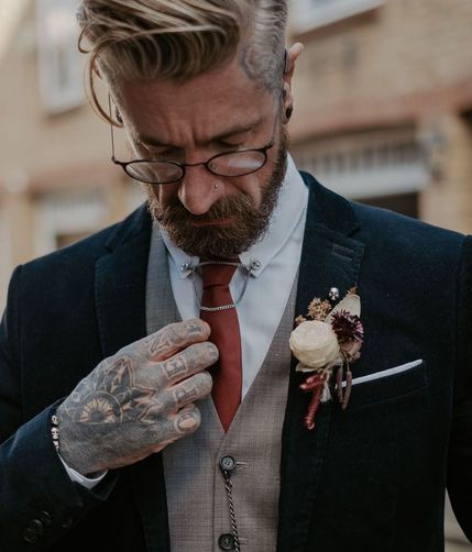 groom wearing three piece suit with tattoos