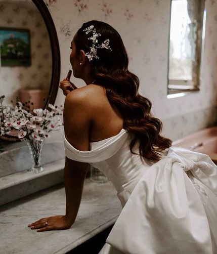 bride with long curled wedding hair looking in mirror