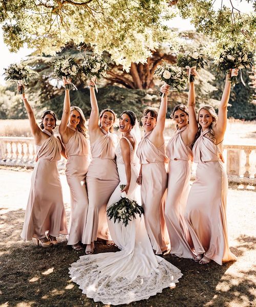 The bride wears a Blue by Enzoani wedding dress with the bridesmaids in blush satin dresses.