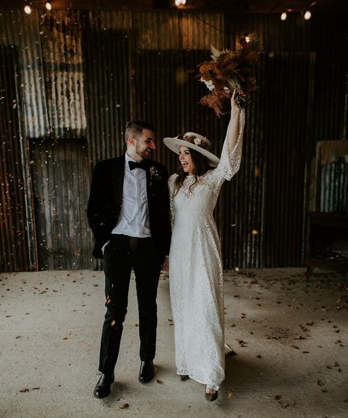 Bride in laser cut lace  wedding dress hold up bouquet with Groom