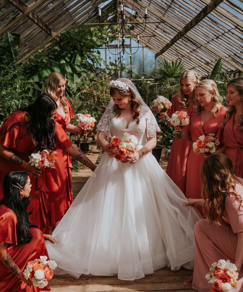 Bride in a princess tulle wedding dress with the bridesmaids in coral peach bridesmaid dresses.