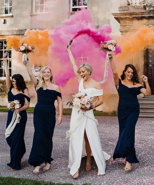 Bride and bridesmaids in navy blue dresses take part in smoke bomb photoshoot for wedding