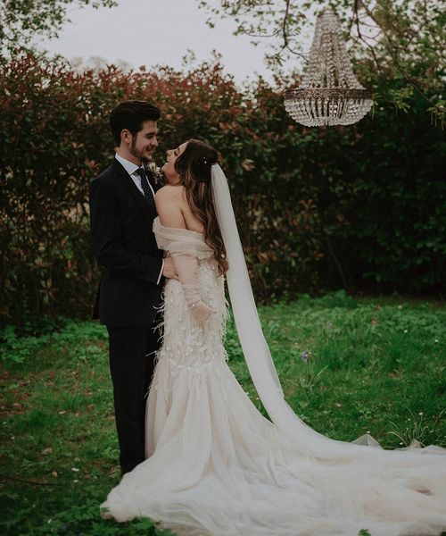 Bride and groom laugh outside next to chandelier decor for their romantic Millbridge Court wedding.