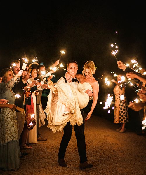 Groom lifting his bride in the air during their sparkler send off 