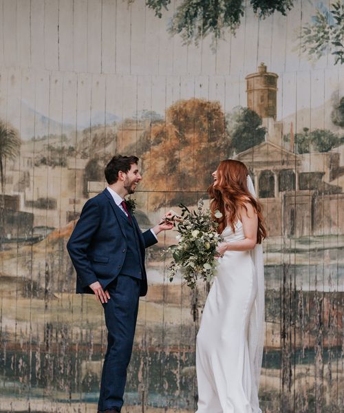 Intimate Larmer Tree wedding with the bride in a satin slip wedding dress and long veil with a green and white bridal bouquet.