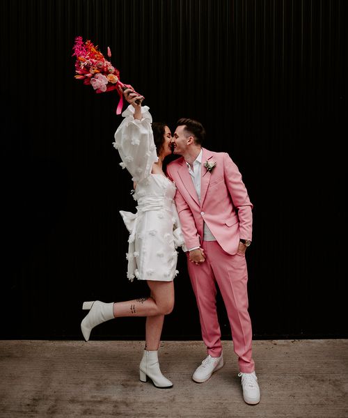 bride in short wedding dress with groom in pink suit at pink retro disco theme wedding