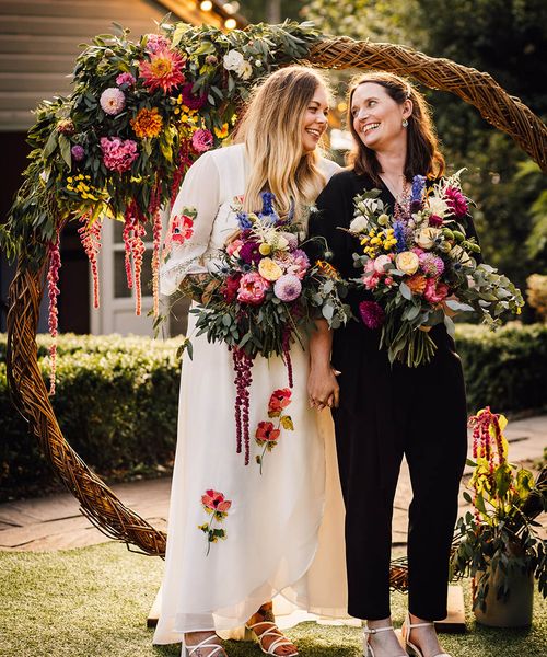 Two brides stand next to moongate decoration at seasonal at The Parlour wedding