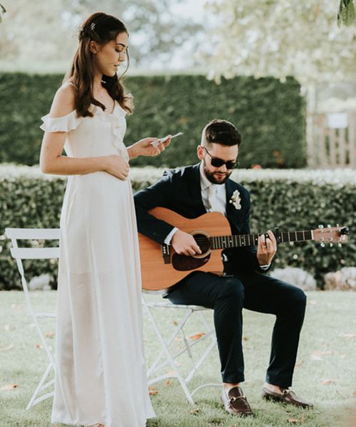 Bridesmaid gives a wedding reading during a ceremony with guitar player.