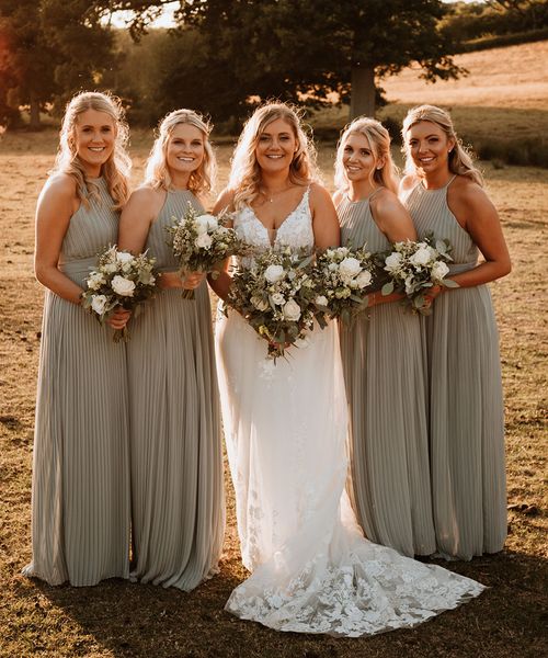 Bridesmaids in sage green pleated bridesmaid dress with the bride for a rustic barn wedding.