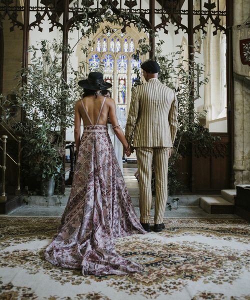 bride and groom wearing pink boho wedding dress and pinstripe groom suit stand at the altar facing away from guests