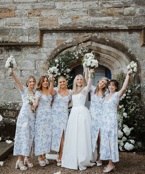 Bride with bridesmaids in blue patterned dresses at their wedding venue.