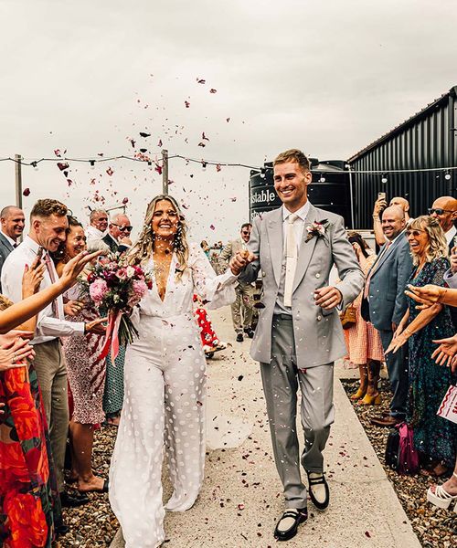 fun east quay Whitstable wedding with bride in a jumpsuit, pink & red colour scheme and mismatched bridesmaid dresses