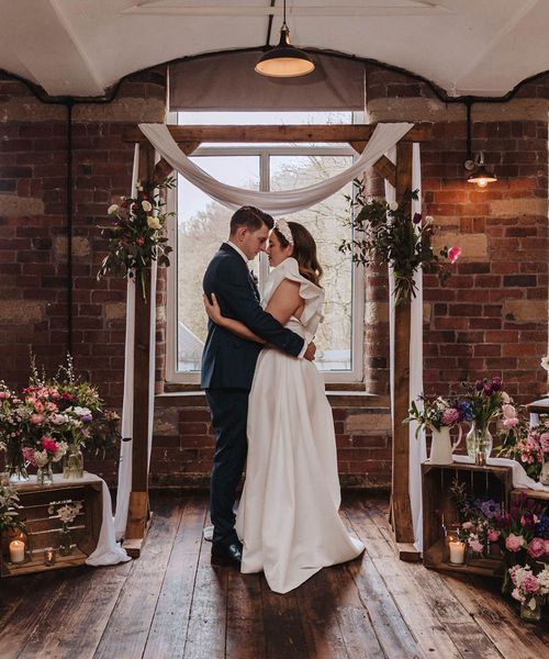 Bowers Mill wedding venue with industrial elements and pretty wildflower decor arranged by the bride herself. Bride wears Jesus Peiro gown and groom wears blue suit.