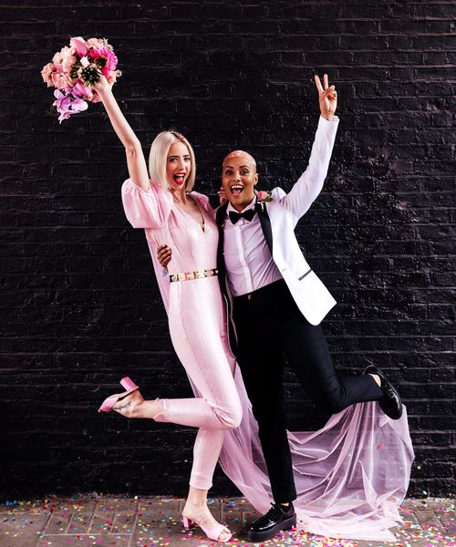 Alternative wedding inspiration with two brides in a pink jumpsuit and white tuxedo jacket 