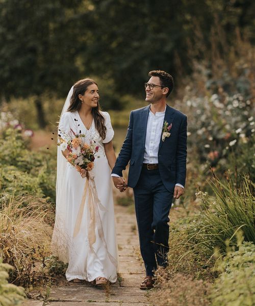 Bride holding bouquet of rustic wedding flowers with the groom for Askham Hall wedding.